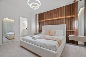 A modern bedroom with a large bed, a bedside table, a mirror, and a wooden accent wall. - A New 9BR to Relax in Orlando in Style (2584SN) (Kissimmee)