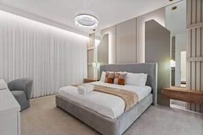 Un dormitorio de hotel moderno con una cama grande, una silla y un candelabro.
