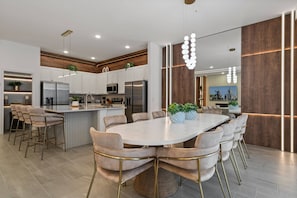 A modern kitchen with white cabinets, stainless steel appliances, and a central island with seating. - Your New 9BR Upscale Orlando Getaway (2576SN) (Kissimmee)