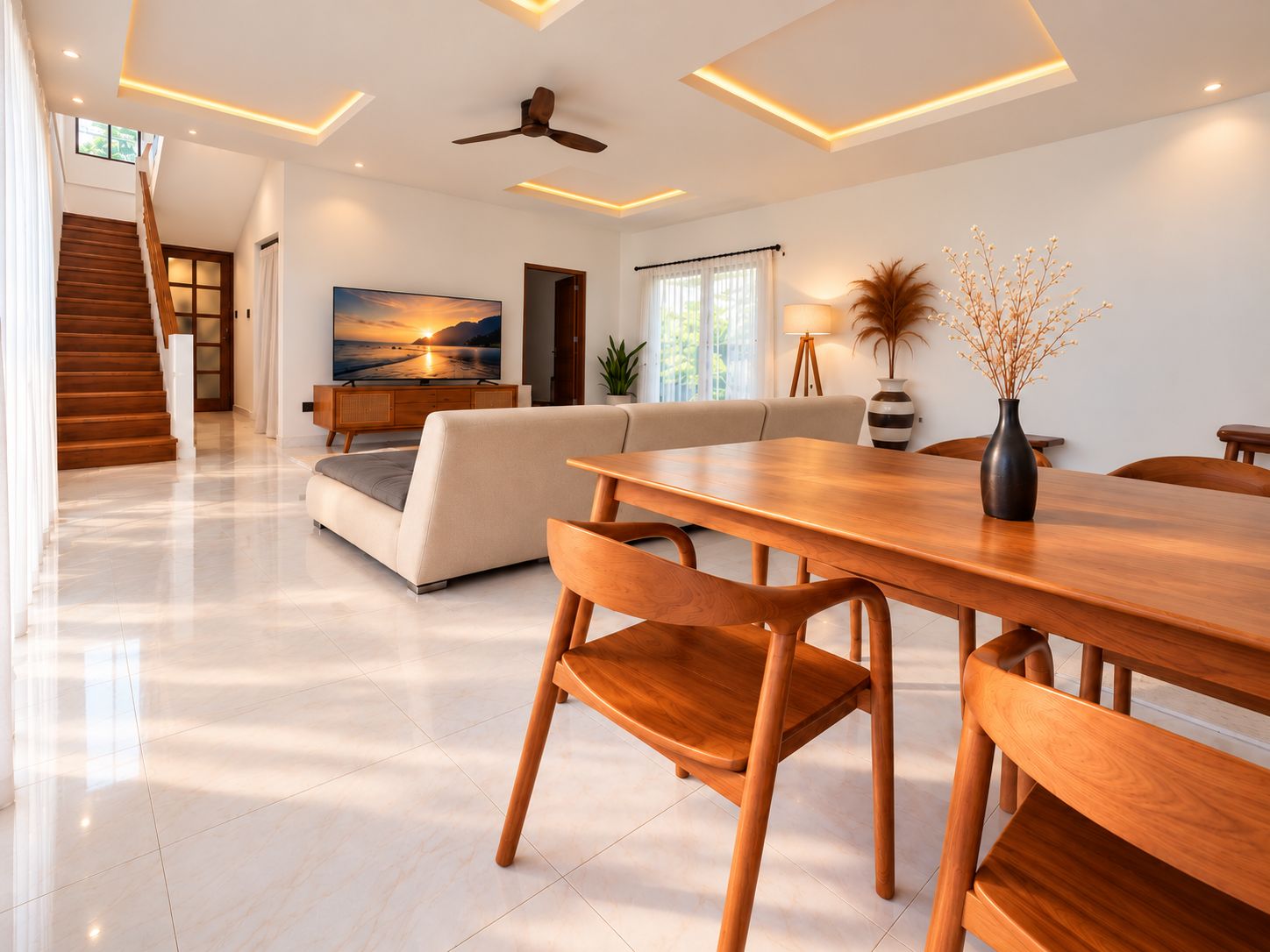 Un comedor moderno con una mesa y sillas de madera, un sofá y un televisor al fondo.