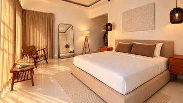 A modern hotel room with a large bed, a desk, a chair, a mirror, and a floor lamp.
