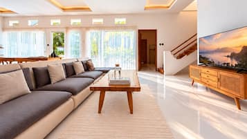 A modern living room with a sofa, coffee table, TV, and a staircase.