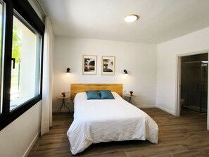 A bedroom with a large bed, two wall-mounted lamps, and a window with curtains. - The perfect home for families and friends! In a peaceful, natural setting. (Prádena)