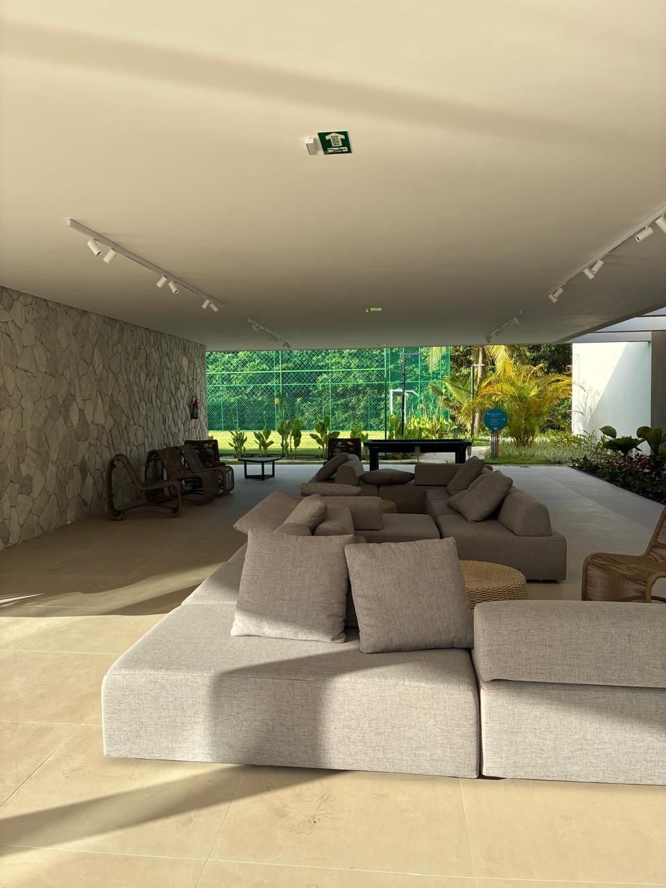 A modern living room with a sectional sofa, a stone wall, and a view of greenery outside.