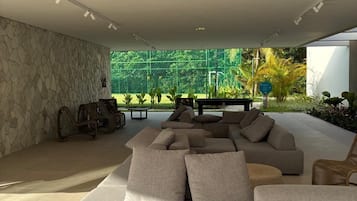 Una sala de estar moderna con un sofá modular, una pared de piedra y vistas al exterior con vegetación.