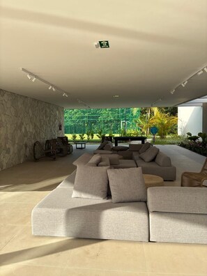 Una sala de estar moderna con un sofá modular, una pared de piedra y vistas al exterior con vegetación.