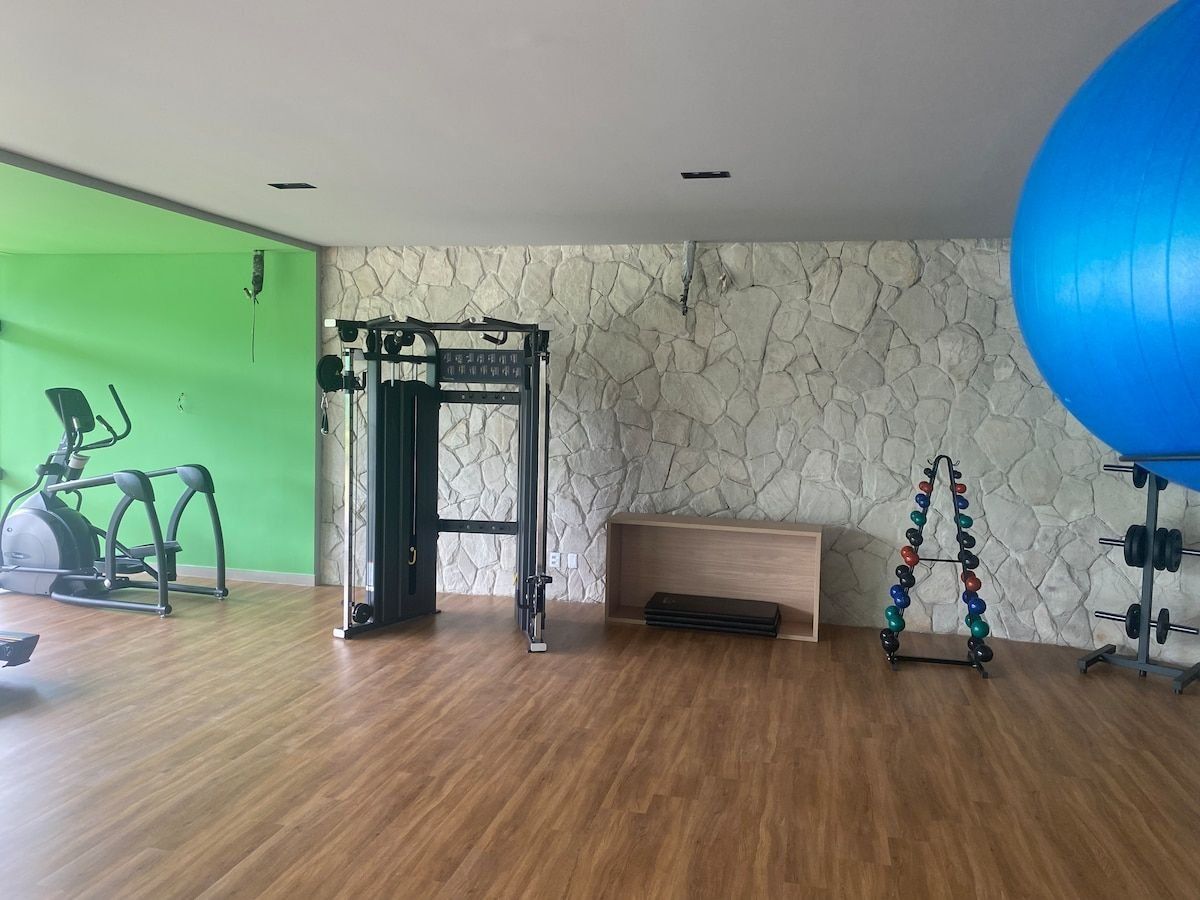 Een sportschool met een houten vloer, fitnessapparatuur, een groene wand en een stenen muur.