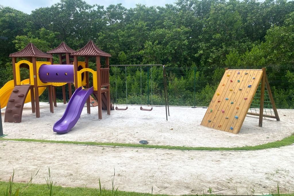 A playground with a slide, climbing wall, and swings.