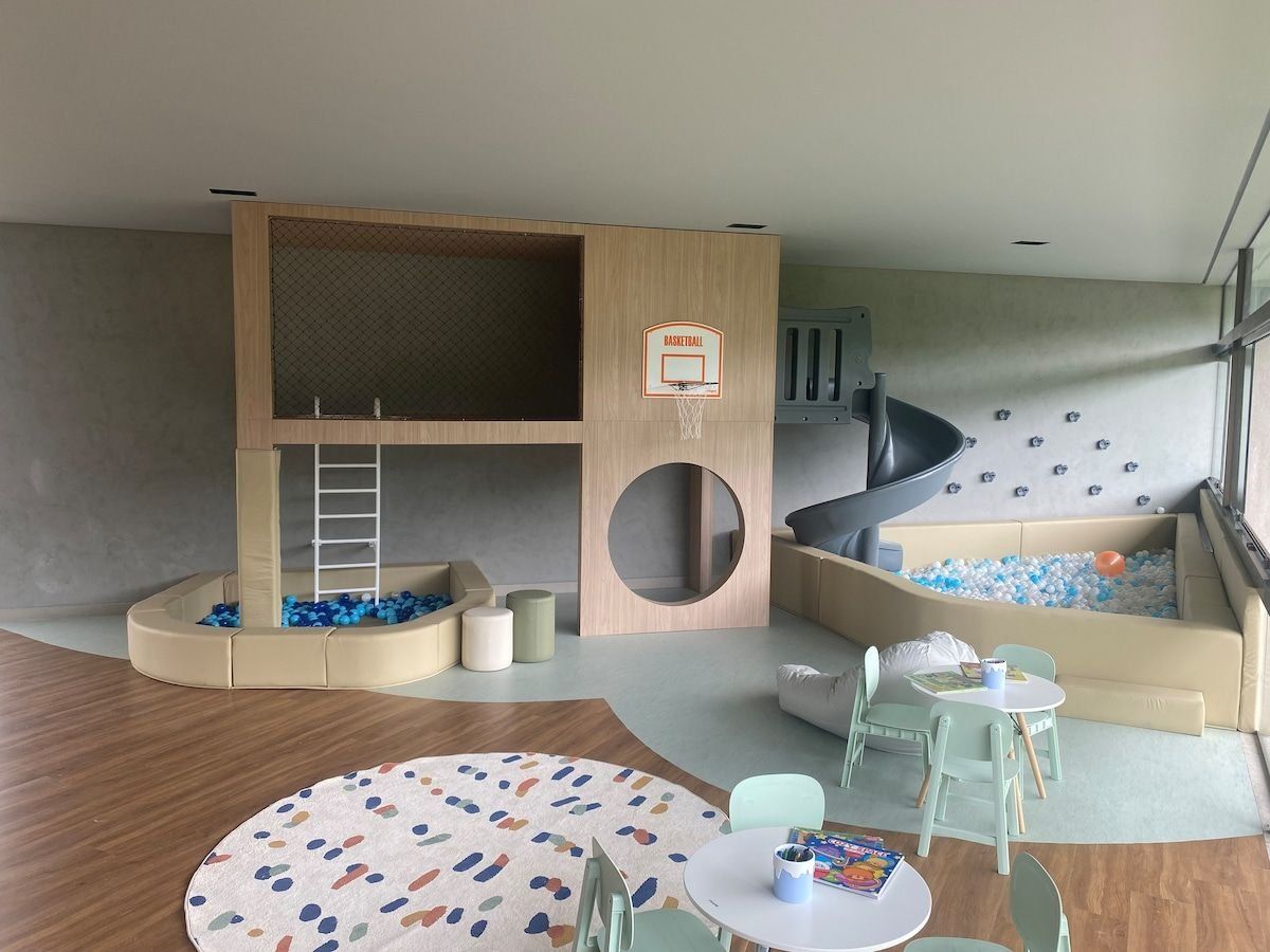Zona de juegos infantiles con aro de baloncesto, estructuras blandas y un tobogán.