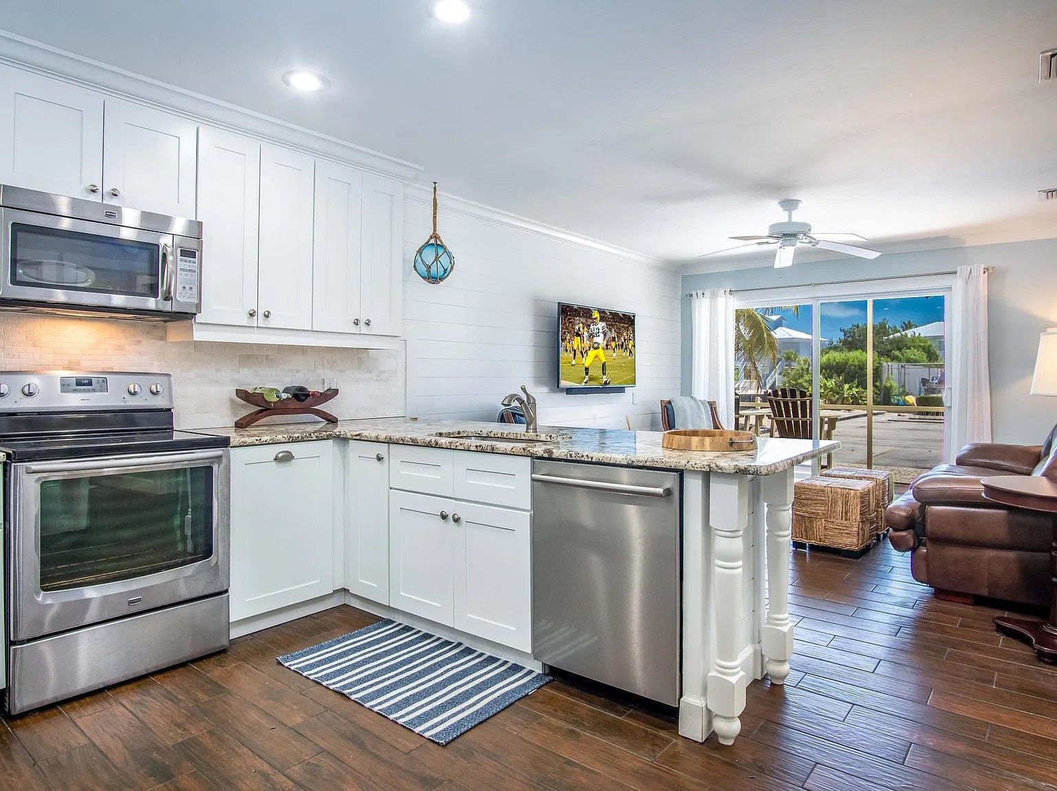 A modern kitchen with white cabinetry, stainless steel appliances, and a view to the outdoor patio area.