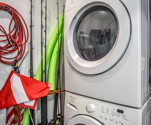 A front view of a white washing machine with a control panel, green hoses, and a red and white flag. - Coco Plum Beach Paradise 1 bedroom apt, great view, boat slip (Marathon)