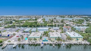 A marina with boats docked, a large building with a flat roof, and a clear view of the water and distant shoreline. - Coco Plum Beach Paradise 1 bedroom apt, great view, boat slip (Marathon)