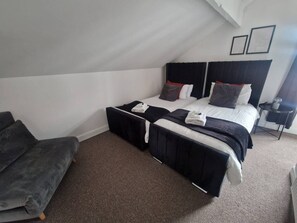 Ein Hotelzimmer mit zwei Betten, einem Sofa und einem kleinen Tisch.