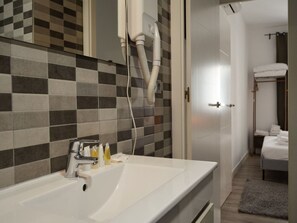 A modern bathroom with a white sink, a towel rack, and a shower area. - Renovated Apartment Near Gran Via (Madrid)