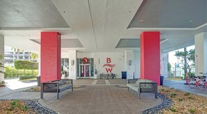 A spacious lobby with a modern design, featuring a prominent logo on the wall, seating areas, and a view of the building's exterior. - Stylish 1BR APT - Resort‑Style experience (Hallandale Beach)
