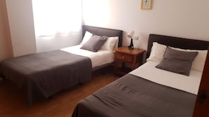 A room with two single beds, a nightstand with a lamp, and a window. - 2B Apartamentos Latin (Nerja)