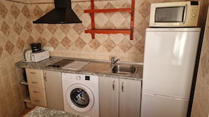 A compact kitchenette with a microwave, toaster, sink, and washing machine. - 2B Apartamentos Latin (Nerja)