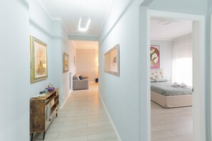 Ein Flur, der zu einem Schlafzimmer mit Bett, Sofa und Bildern an den Wänden führt.