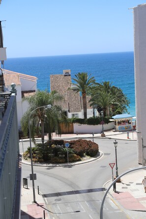 A coastal street with a roundabout, palm trees, and a view of the sea. - .2C Apartamentos Latin (Nerja)