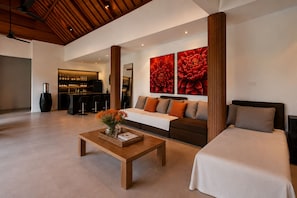 A modern hotel room with a sofa, a bed, a coffee table with flowers, and a bar area in the background. - 3BR New Luxury Villa Jimbaran/Nusa Dua (Badung)