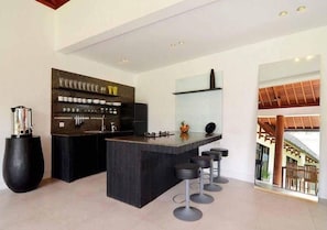 Una cocina moderna con una isla central, taburetes de bar y una variedad de utensilios de cocina exhibidos en estantes.