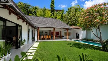 Una casa moderna con piscina, terraza cubierta y césped cuidado.