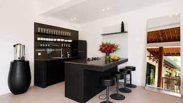 A modern kitchen with a central island, bar stools, and a coffee machine.