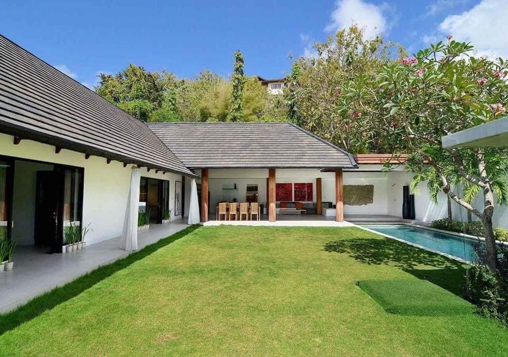 A modern house with a swimming pool, a covered patio, and a well-maintained lawn.
