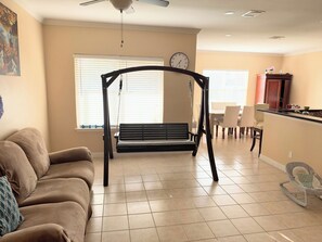 A living room with a swing, a sofa, a dining area, and a kitchen. - Sublet 1 room upstairs located in Houston, Texas. (Houston)