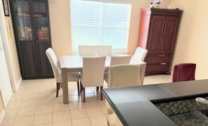 A dining area with a table and chairs, a cabinet with books, and a window with blinds. - Sublet 1 room upstairs located in Houston, Texas. (Houston)