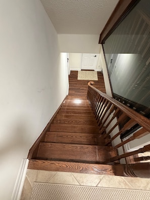 Eine Holztreppe mit Handlauf, die zu einer Zwischenebene mit einer Tür und einem Glasfenster führt.