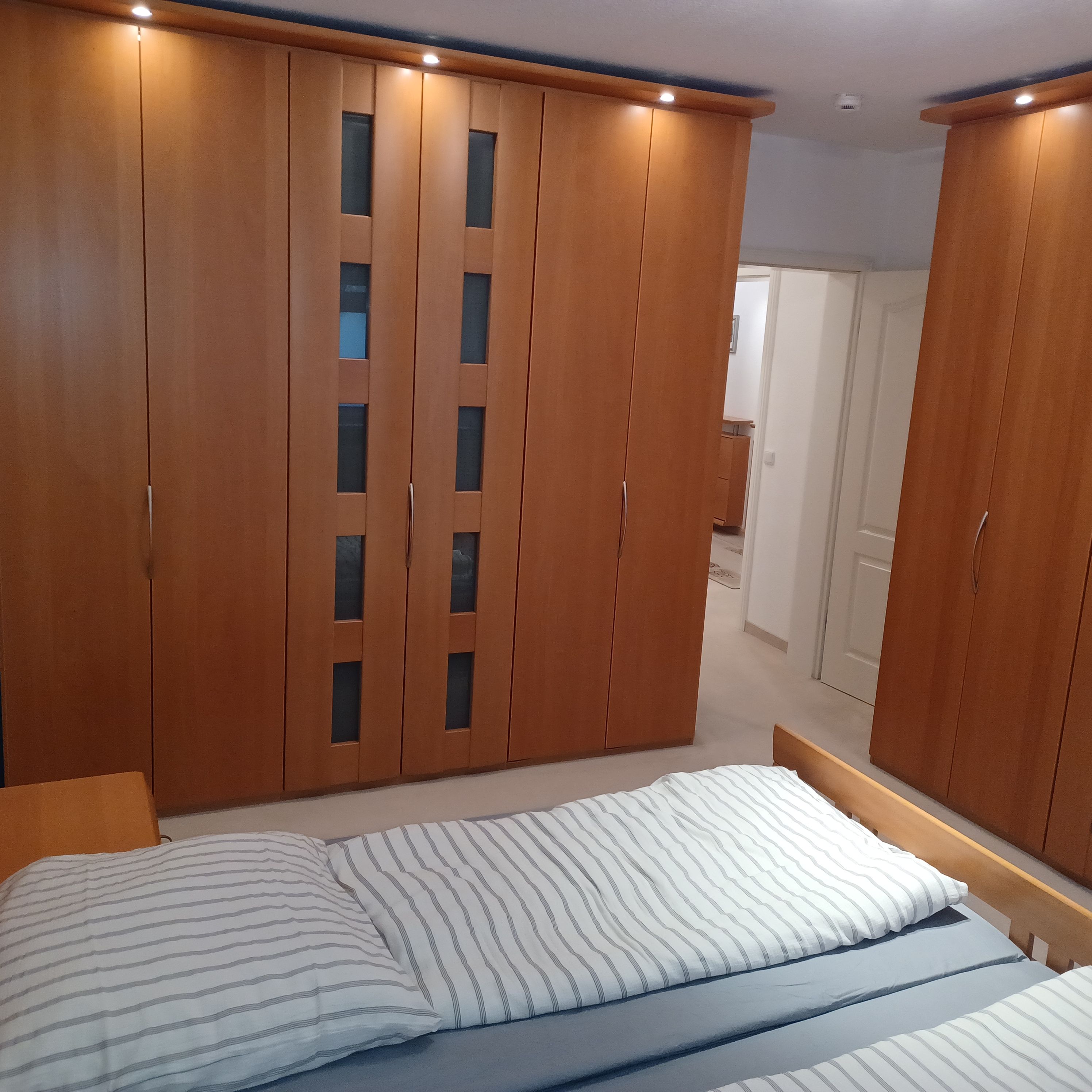 A bedroom with a bed, a wardrobe, and a bathroom visible in the background.