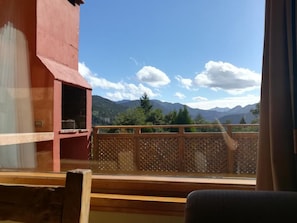 A room with a view of mountains, a balcony with a lattice railing, and a wooden bench.