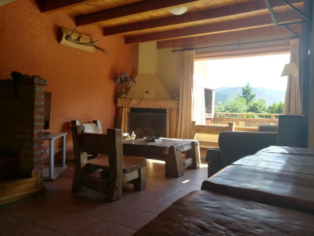 Un interior rústico con chimenea, muebles de madera y vistas al exterior.