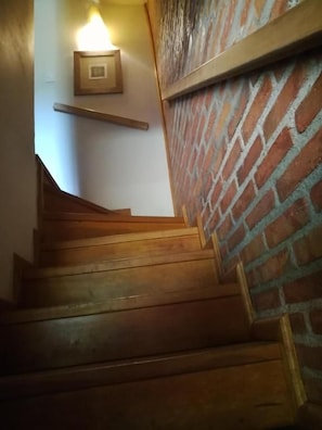 A wooden staircase with a brick wall on one side.