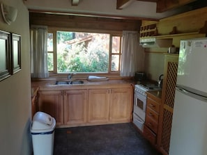 A kitchen with wooden cabinets, a sink, a stove, and a refrigerator.