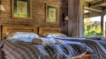 Una habitación con dos camas de madera, una pared de ladrillo y cuadros enmarcados.