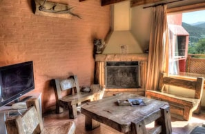A rustic interior with a fireplace, wooden furniture, and a television.