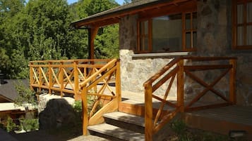 Un bâtiment en pierre avec des escaliers et des rampes en bois, entouré d’arbres.