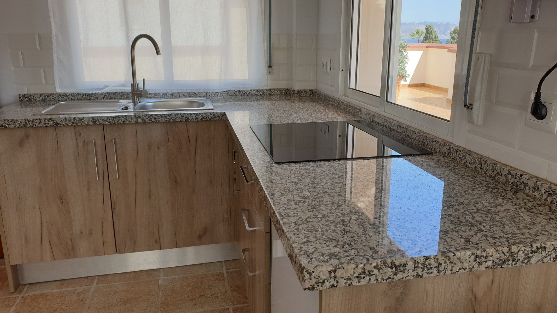 Eine Küche mit Granit Arbeitsplatte, Edelstahlspüle und Holzschränken.