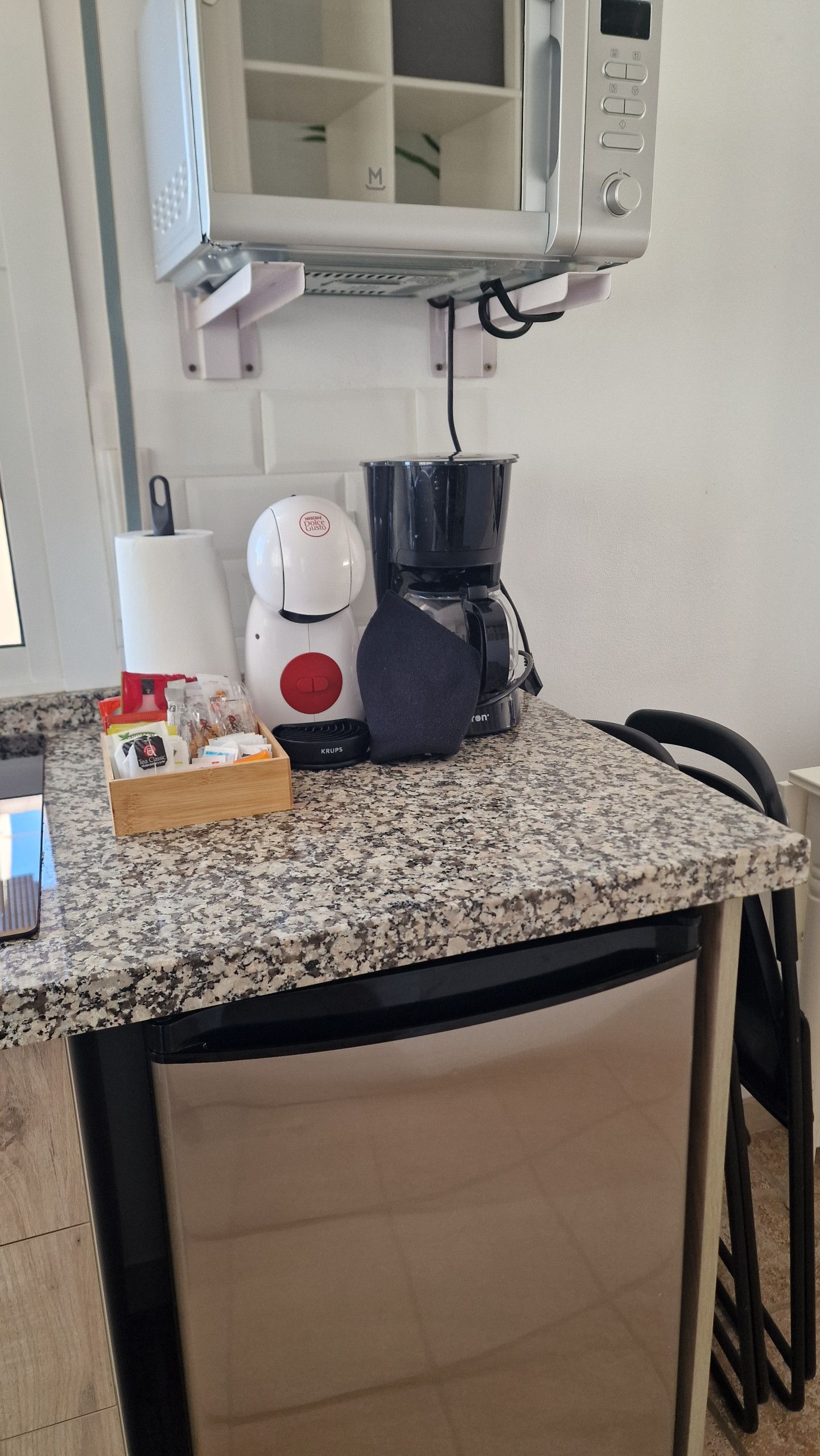 A kitchenette with a microwave, coffee maker, and a small refrigerator.
