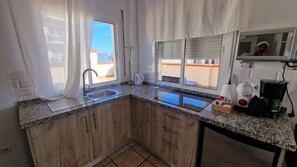 Una cuina amb taulell de granat, armaris de fusta, vàter d'acer inoxidable i una finestra amb vista a l'exterior.