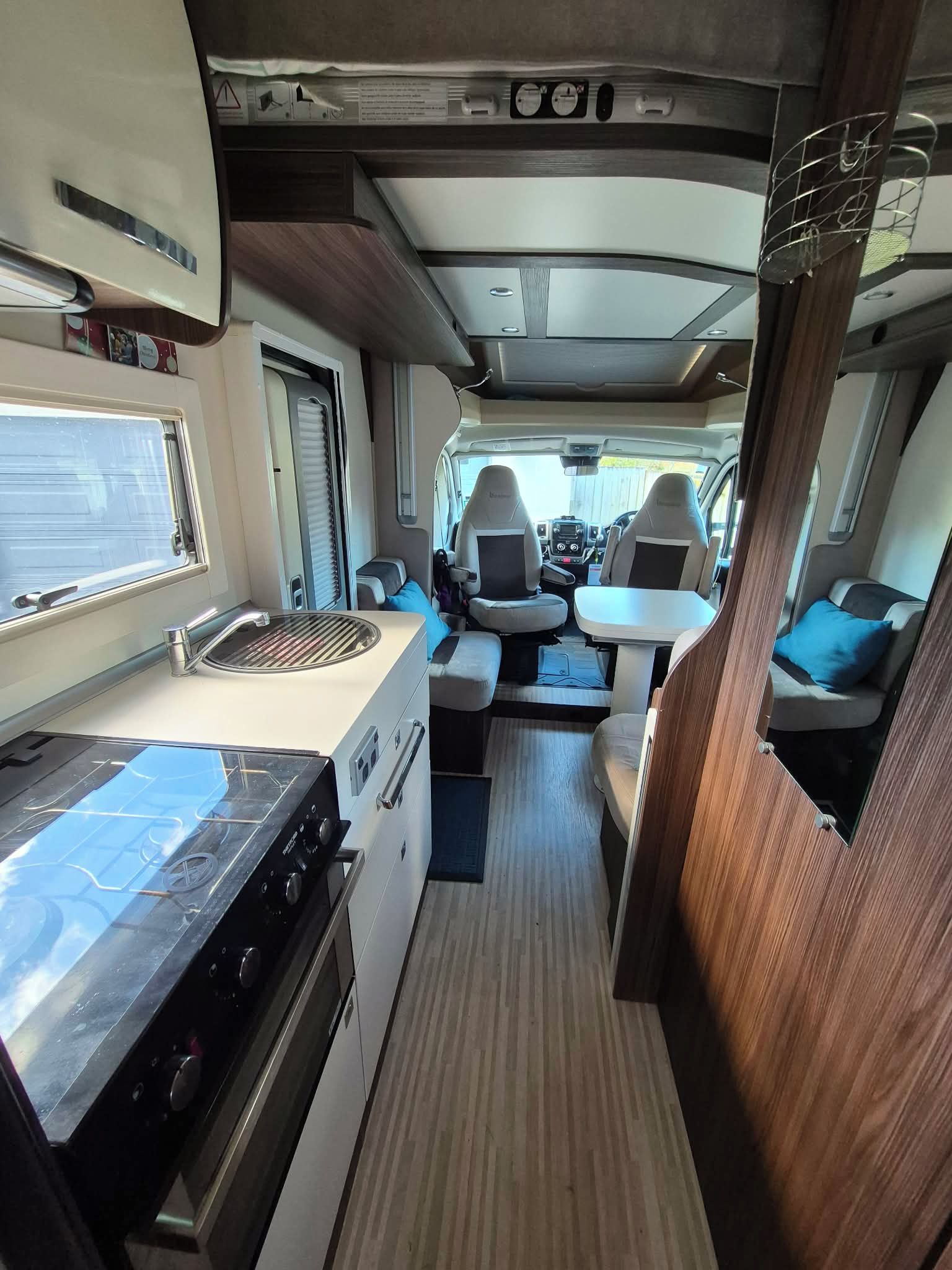 Interior de una caravana compacta, con kitchenette, zona de estar y una mesita.