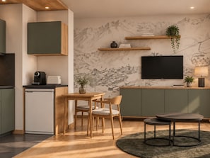 A modern kitchen with a dining area, a flat-screen TV mounted on the wall, and a small coffee machine. - Cozy studio in Val Thorens - 4 guests (Val Thorens)