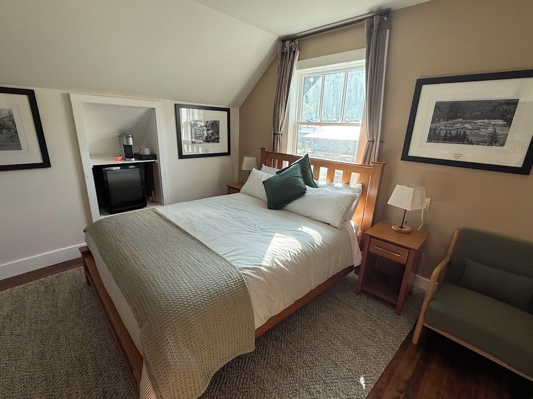 A bedroom with a bed, bedside tables, a chair, a television, and framed pictures on the walls.