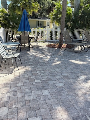 A patio with a white fence, lounge chairs, and a table with chairs. - Lovely Waterfront Cottage #1821, private patio, overlooking river. Ruskin, FL (Ruskin)