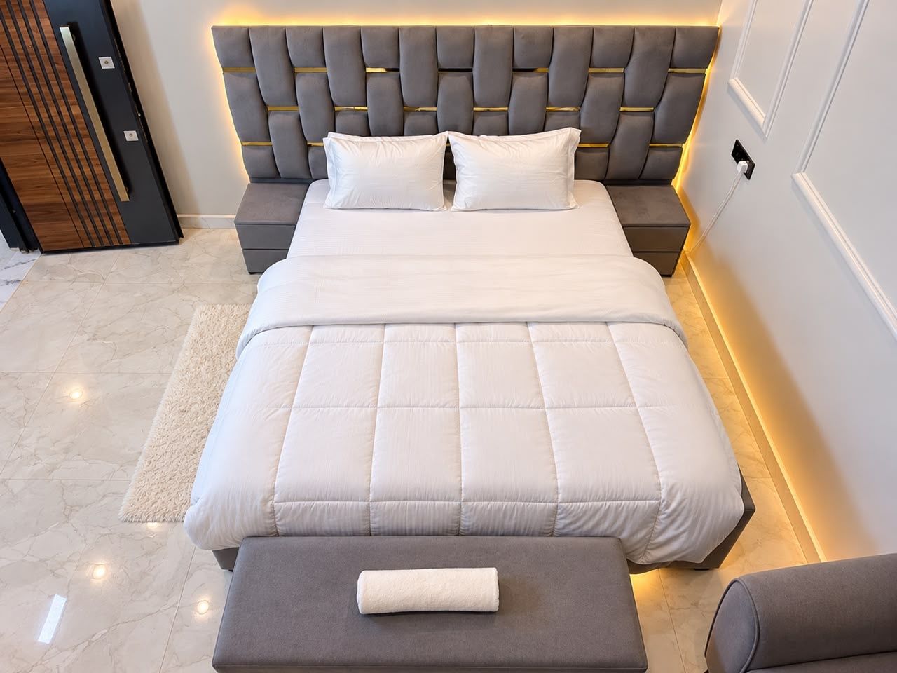 A modern bedroom with a large bed, a bedside table, and a nightstand.