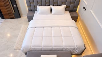 A modern bedroom with a large bed, a bedside table, and a nightstand.