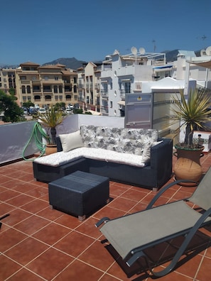 A rooftop terrace with a sectional sofa, a lounge chair, and a potted plant. - Carabeo 78X-2 (Nerja)