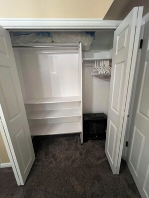 Ein Kleiderschrank mit geöffneten Türen, der Regale und Ablageflächen zeigt.